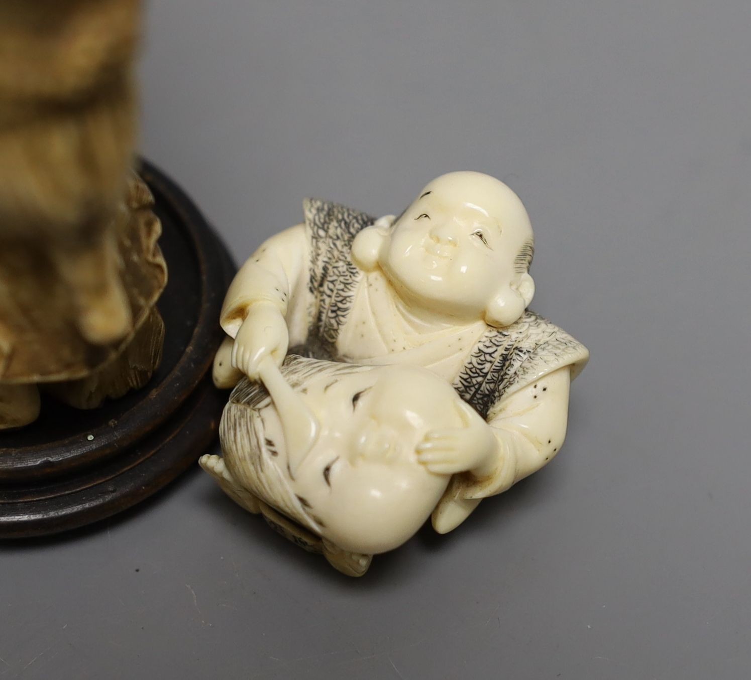 A Japanese ivory okimono of a monkey carrying a lotus leaf containing toads, on its back and an Ivory Netsuke of a mask maker, both Meiji period - tallest 9.5cm high